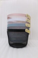 Stacked round metal wire mesh storage baskets with wooden handles in dusky pink, white, grey, and black on a marble countertop.