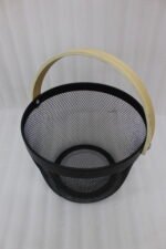 Stacked round metal wire mesh storage baskets with wooden handles in dusky pink, white, grey, and black on a marble countertop.