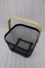 Stack of modern mesh wire storage baskets in pink, black, white, and blue with light wooden handles on a kitchen countertop.