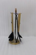 7-piece black silicone cooking utensil set with wooden handles on a rotating stand sitting on a marble kitchen countertop.