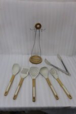 7 piece white silicone kitchen utensil set with natural wooden handles hanging on a chrome stand