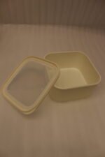 Stacked set of four cream-colored fluted plastic storage boxes with lids on a white kitchen countertop.