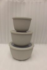Stack of three light gray ribbed food storage containers with translucent lids on a kitchen countertop