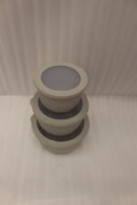 Stack of three light gray ribbed food storage containers with translucent lids on a kitchen countertop