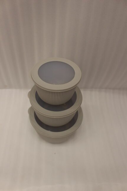 Stack of three light gray ribbed food storage containers with translucent lids on a kitchen countertop