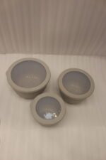 Stack of three light gray ribbed food storage containers with translucent lids on a kitchen countertop