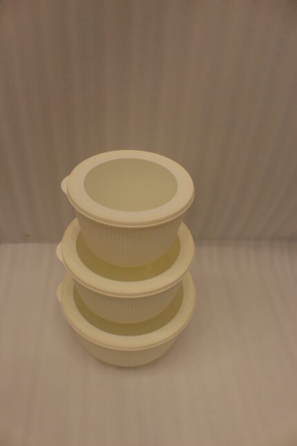 Stacked 3-piece white fluted food storage containers with clear airtight lids on a kitchen counter