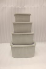 Stacked 4-piece ribbed grey plastic storage box set with fitted lids on a marble kitchen countertop.