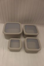 Stacked 4-piece ribbed grey plastic storage box set with fitted lids on a marble kitchen countertop.