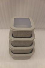 Stacked 4-piece ribbed grey plastic storage box set with fitted lids on a marble kitchen countertop.