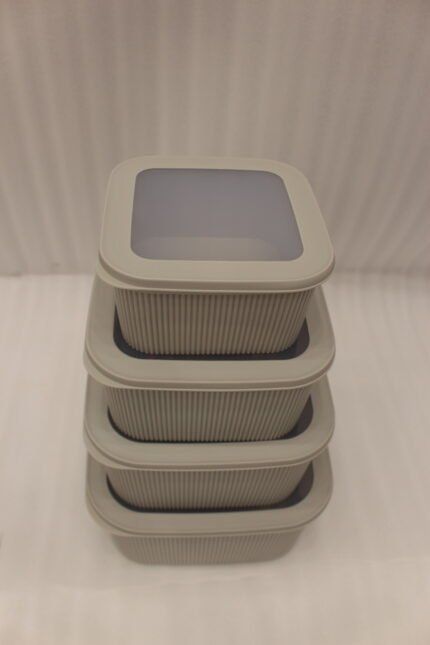Stacked 4-piece ribbed grey plastic storage box set with fitted lids on a marble kitchen countertop.