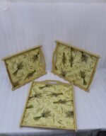 Set of three rectangular wooden serving trays with wheat botanical pattern and handles resting on a marble kitchen countertop.