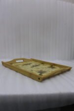 Set of three rectangular wooden serving trays with wheat botanical pattern and handles resting on a marble kitchen countertop.