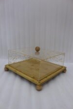 Square bamboo cake stand with gold flecked acrylic dome cover set on a kitchen counter