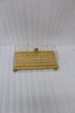 Rectangular wooden cake display tray with a gold flake patterned acrylic cover and wooden ball feet on a marble countertop