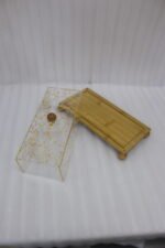Rectangular wooden cake display tray with a gold flake patterned acrylic cover and wooden ball feet on a marble countertop