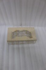 Clear acrylic tissue box holder embedded with gold flakes and a textured beige lid sitting on a wooden table