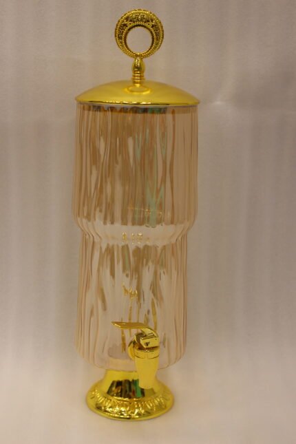 3.5L ribbed pink glass beverage dispenser with ornate gold base, spout, and top handle standing on a kitchen marble countertop