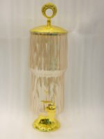 3.5L ribbed pink glass beverage dispenser with ornate gold base, spout, and top handle standing on a kitchen marble countertop