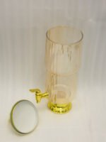 3.5L ribbed pink glass beverage dispenser with ornate gold base, spout, and top handle standing on a kitchen marble countertop