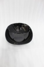Glossy black 38-piece ceramic dinner set arranged on a rustic wooden dining table near a bright window.