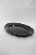 38-piece glossy black opal glass dinner set displayed on a wooden dining table, featuring plates, bowls, cups, and serving dishes.