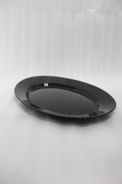 38-piece glossy black opal glass dinner set displayed on a wooden dining table, featuring plates, bowls, cups, and serving dishes.