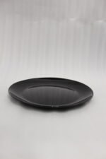 38-piece glossy black opal glass dinner set displayed on a wooden dining table, featuring plates, bowls, cups, and serving dishes.