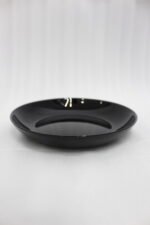 38-piece glossy black opal glass dinner set displayed on a wooden dining table, featuring plates, bowls, cups, and serving dishes.