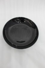 38-piece glossy black opal glass dinner set displayed on a wooden dining table, featuring plates, bowls, cups, and serving dishes.
