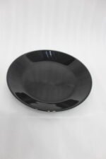 38-piece glossy black opal glass dinner set displayed on a wooden dining table, featuring plates, bowls, cups, and serving dishes.