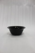 38-piece glossy black opal glass dinner set displayed on a wooden dining table, featuring plates, bowls, cups, and serving dishes.