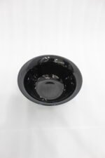 38-piece glossy black opal glass dinner set displayed on a wooden dining table, featuring plates, bowls, cups, and serving dishes.