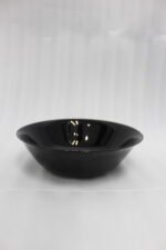 38-piece glossy black opal glass dinner set displayed on a wooden dining table, featuring plates, bowls, cups, and serving dishes.
