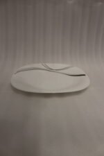 White opal glass dinner set with minimalist black linear wave design displayed on a kitchen island