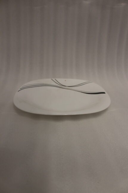 White opal glass dinner set with minimalist black linear wave design displayed on a kitchen island