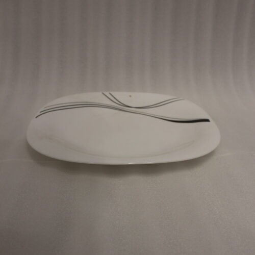 White opal glass dinner set with minimalist black linear wave design displayed on a kitchen island