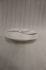 White opal glass dinner set with minimalist black linear wave design displayed on a kitchen island