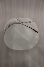 White opal glass dinner set with minimalist black linear wave design displayed on a kitchen island