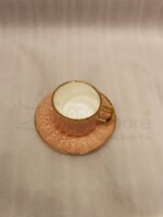 Pink ceramic cup and saucer 6-person set with gold trim inside a gift box on a kitchen counter.