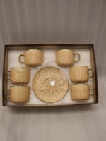 Elegant 6-person beige ceramic tea cup and saucer set with gold handles arranged inside a presentation gift box on a kitchen counter.