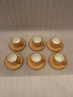 Elegant 6-person beige ceramic tea cup and saucer set with gold handles arranged inside a presentation gift box on a kitchen counter.