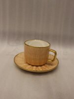 Elegant 6-person beige ceramic tea cup and saucer set with gold handles arranged inside a presentation gift box on a kitchen counter.