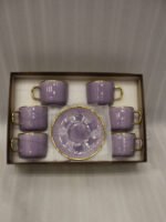 Luxury purple and gold 6-person cup and saucer set neatly arranged in a presentation box on a kitchen counter.
