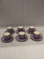 Luxury purple and gold 6-person cup and saucer set neatly arranged in a presentation box on a kitchen counter.