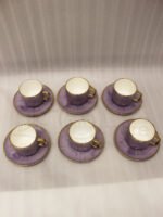 Luxury purple and gold 6-person cup and saucer set neatly arranged in a presentation box on a kitchen counter.