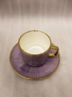 Luxury purple and gold 6-person cup and saucer set neatly arranged in a presentation box on a kitchen counter.