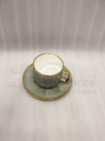 A luxury 6-person sage green ceramic cup and saucer set with gold trim, neatly packed in a gift box on a kitchen counter.