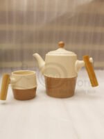 A complete modern tea set for 6 persons, featuring cream and mocha two-tone ceramic teapot and six matching mugs with bamboo handles, neatly organized on two bamboo serving trays on a kitchen counter.