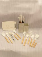 Off-white 19-piece silicone kitchen utensil and knife set with rose gold accents sitting in a dual caddy block on a countertop.